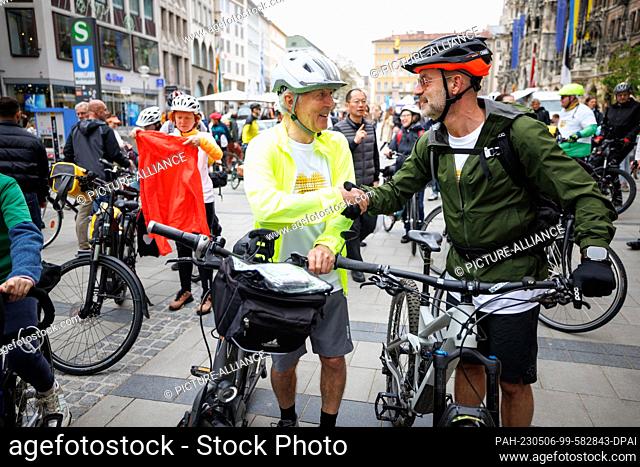 06 May 2023, Bavaria, Munich: Dietmar Achleitner (l) and Pedro Dias, escort of the tour to Innsbruck, shake hands before the start of a bicycle pilgrimage of 15...