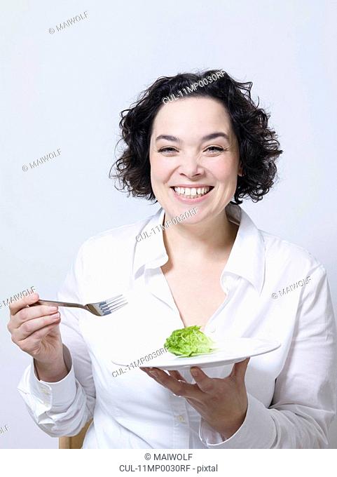 woman holding plate with leaf of salad