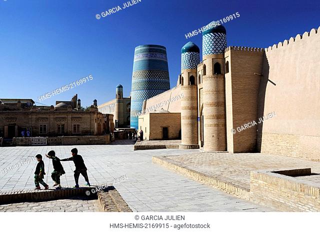 Uzbekistan, Khorezm, Khiva, Itchan Kala (inner town) listed as World Heritage by UNESCO, children playing near the Kuhna Ark fortress and the unfinished minaret...