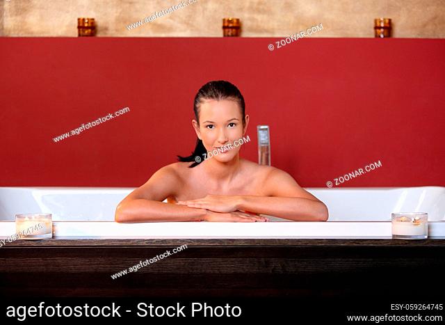 Young woman wellness bathing, smiling, looking at camera