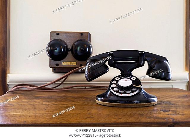 Close-up of fixed-line black antique Northern Electric rotary dial telephone on wooden desk table in kitchen inside an old 1892 Canadiana cottage style home