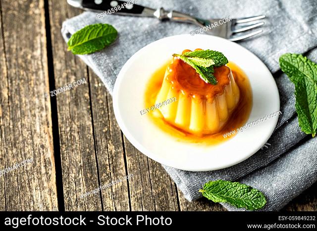 Sweet vanilla pudding. Sweet dessert with caramel topping on wooden table