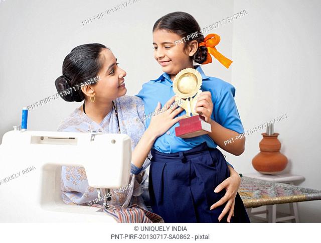 Girl showing a winning trophy to her mother