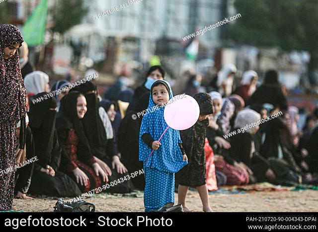 20 July 2021, Palestinian Territories, Gaza City: A Palestinian girl holds a balloon during Eid al-Adha morning prayer at Al-Saraya Square