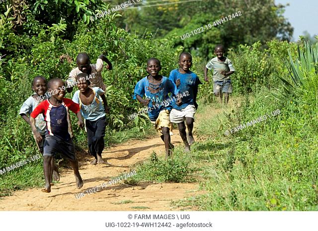 Happy children running barefoot down a dirt path
