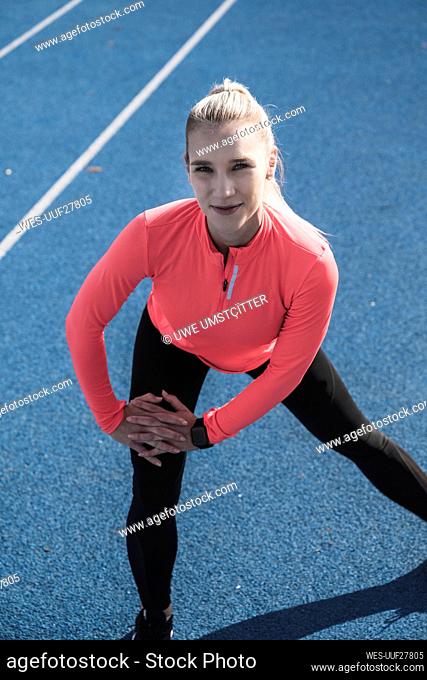 Young athlete doing stretching exercise on running track