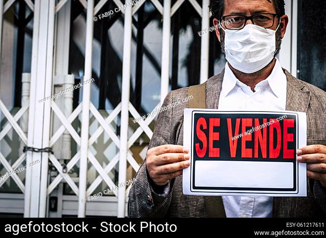 Portrait of man wear medical mask for coronavirus economy crisis with closed business and se vende spanish panel - concept of unemployed people after covid-19...