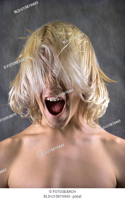 Male Caucasian teen with hair over face screaming
