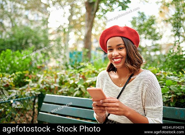 Young woman holding mobile phone on bench