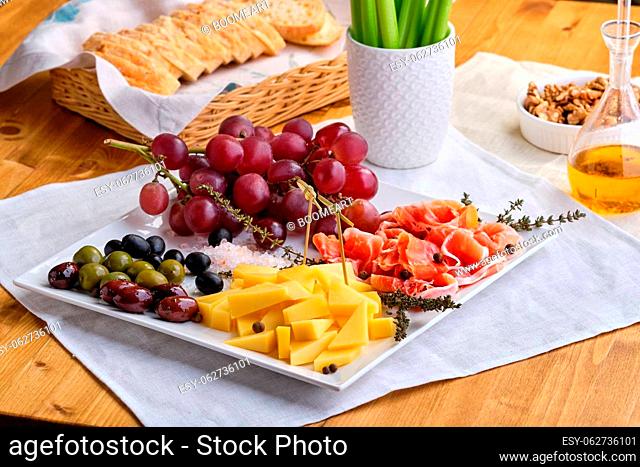 Set of various appetizers for wine - cheese, prosciutto, grape, olives, walnuts and celery