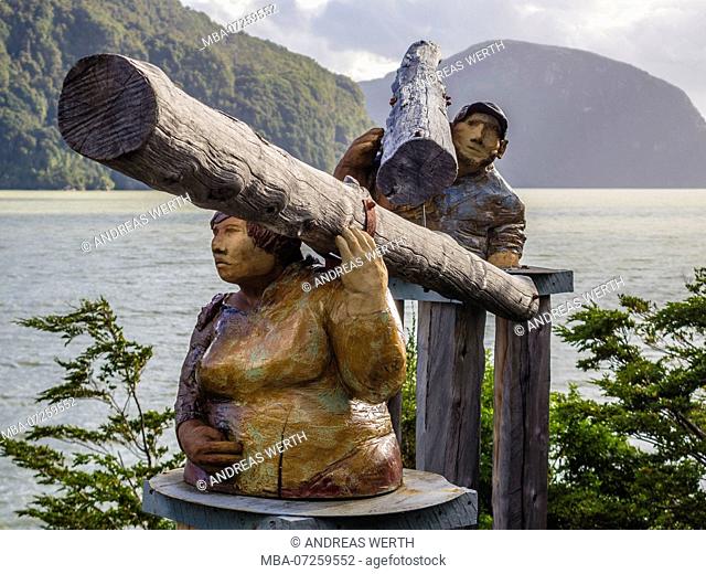 Sculputure of man an woman carrying trunks of a tree, seaside of Caleta Tortel, Caleta Tortel, Aysen region, Patagonia, Chile