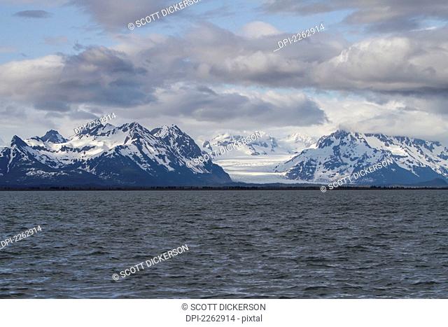 A View Of Sheridan Glacier And The Chugach Mountains With Blue Sky And White Clouds From The Copper River Flats, Cordova Alaska United States Of America