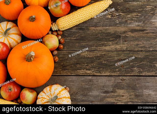 Autumn harvest still life with pumpkins, apples, hazelnut, corn, on wooden background, top view with copy space