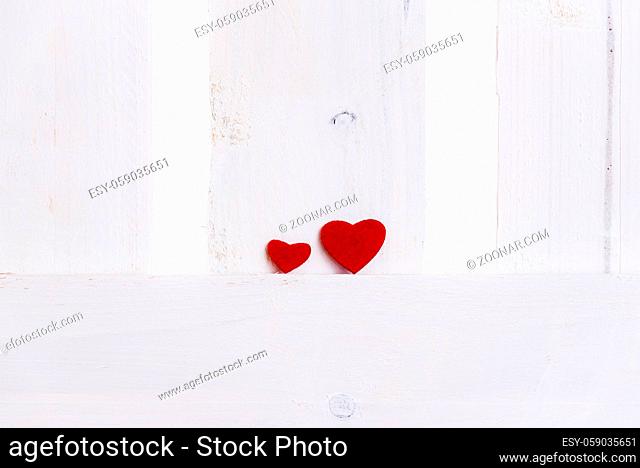 Relationship theme image with a big red heart next to a smaller one on a white wooden fence. A concept of love, partnership, team, greeting card idea