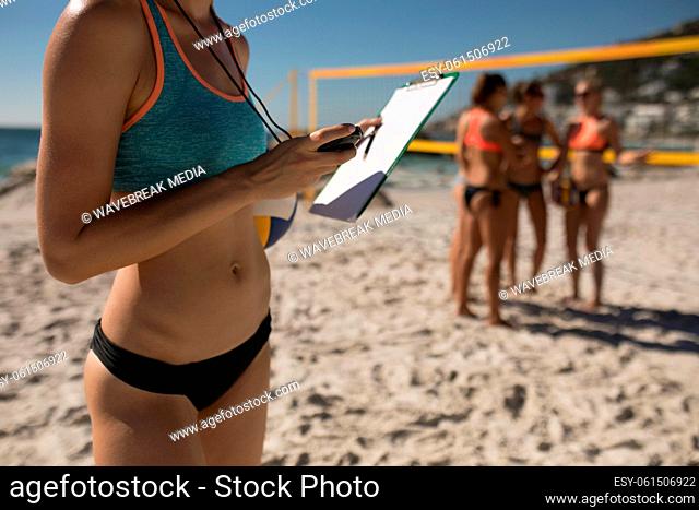 Female volleyball coach with clipboard on the beach