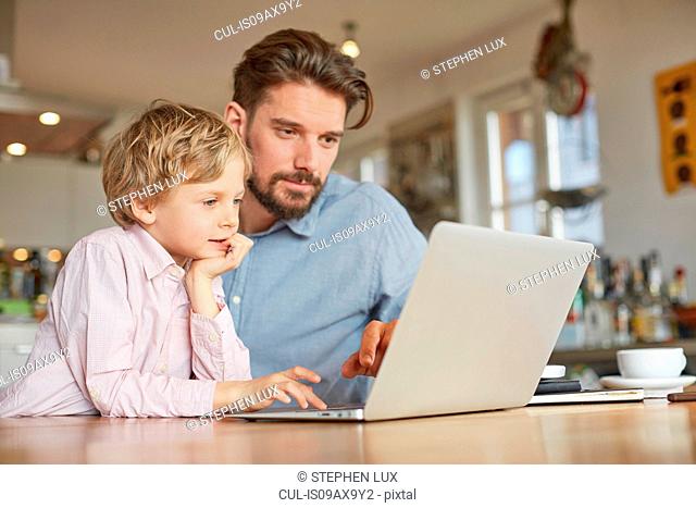 Father and son using laptop in home office