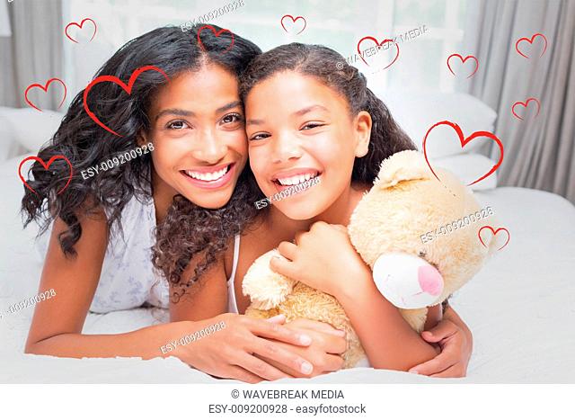 Composite image of pretty woman lying on bed with her daughter smiling at camera