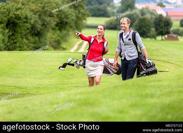Man looking at her girlfriend pointing something on golf course