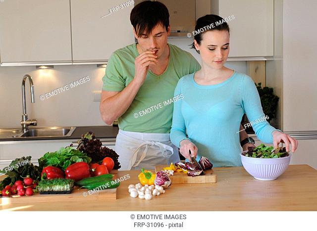 Young couple in kitchen preparing salad