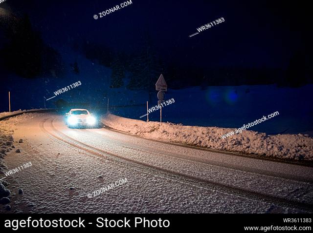 car driving on dangerous road at night with fresh snow