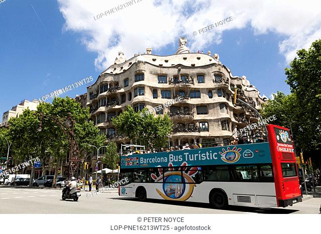 Spain, Catalonia, Barcelona. Open top tourist bus passing La Pedrera in Barcelona