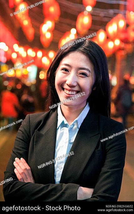 Businesswoman standing on the street, red lanterns on the background