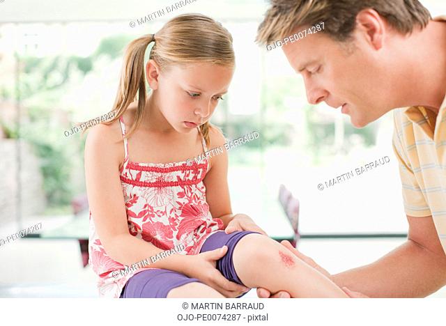 Father tending to daughter’s scraped knee