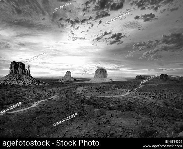 Panoramic road, gravel road in Monument Valley, prominent rocks, West Mitten Butte, East Mitten Butte, Merrick Butte on the horizon, dusk, monochrome, film set