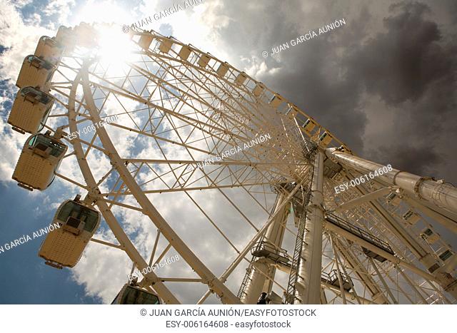 Ferris wheel over cloudy sky, at the fair in Cordoba