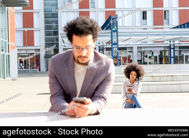 Male and female entrepreneurs using smart phone during sunny day