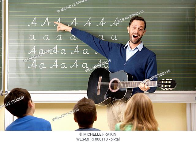 Teacher with guitar at blackboard showing variations of letter A