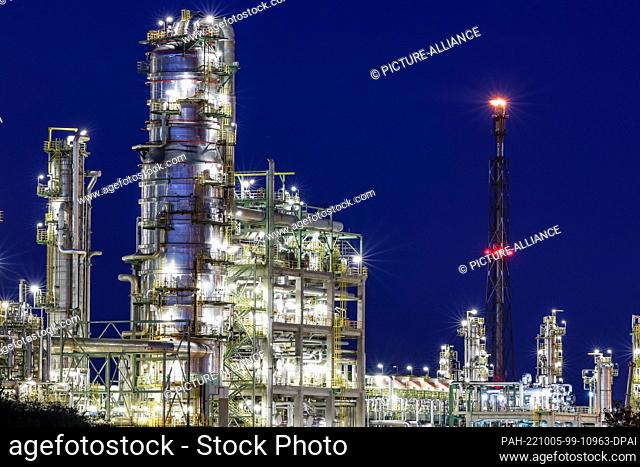 04 October 2022, Saxony-Anhalt, Leuna: The torch of the Total refinery burns in the evening. The refinery, built in 1997 by the French oil company Elf-Aquitaine
