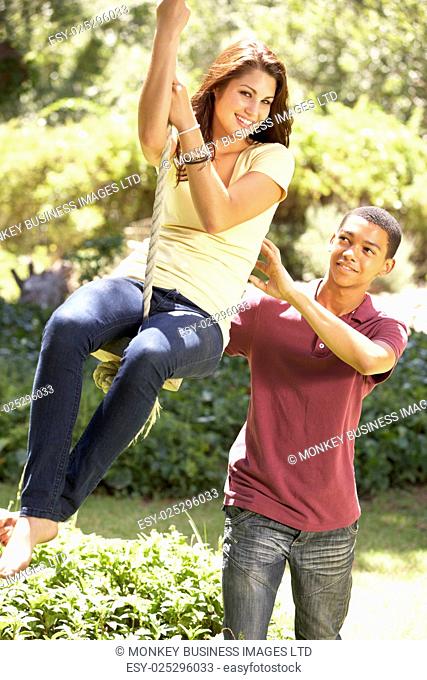 Teenage Couple Having Fun On Rope Swing