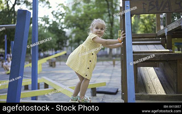 Cute little girl plays on the playground. Child girl playing on the playground in the city park. Odessa, Ukraine, Europe