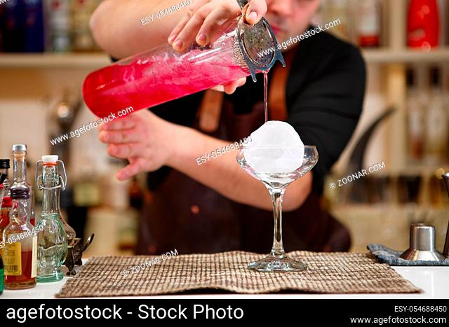 barman pouring a pink cocktail drink