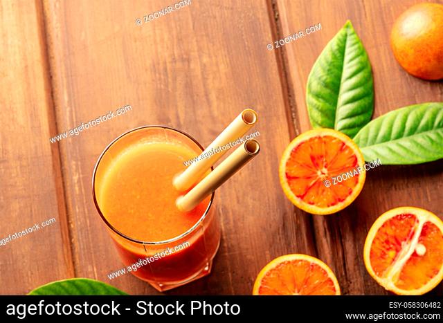 A closeup of reusable bamboo straws in a glass of vibrant orange juice, with copy space. Selective focus