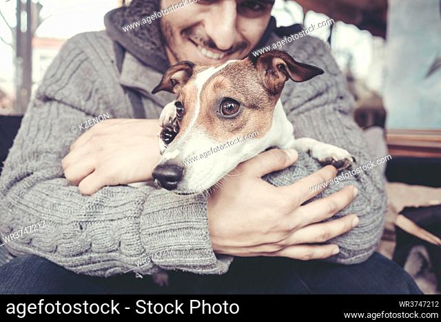 Man cuddling with his terrier dog in winter