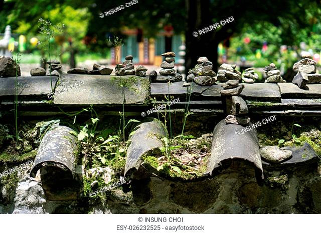 Traditional old temple wall with small pebbles of rocks and flowers on the roof tiles. Taken in Gangcheon Mountain, Sunchang, South Korea