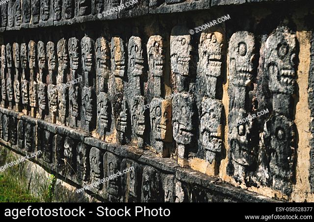 Wall with carved skulls in a stone Mayan temple in Chichen Itza, Yucatan, Mexico