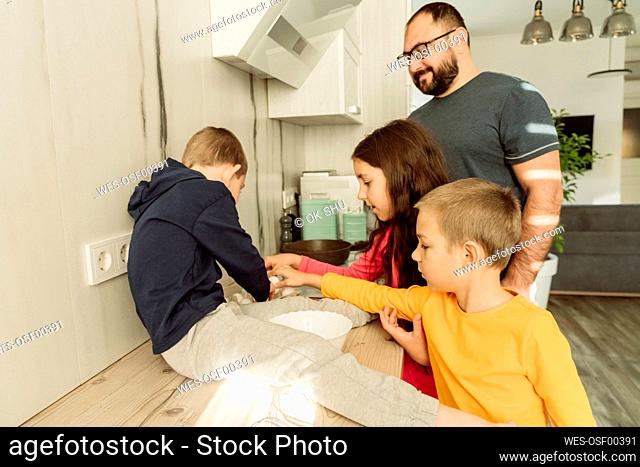 Smiling father with children preparing breakfast in kitchen