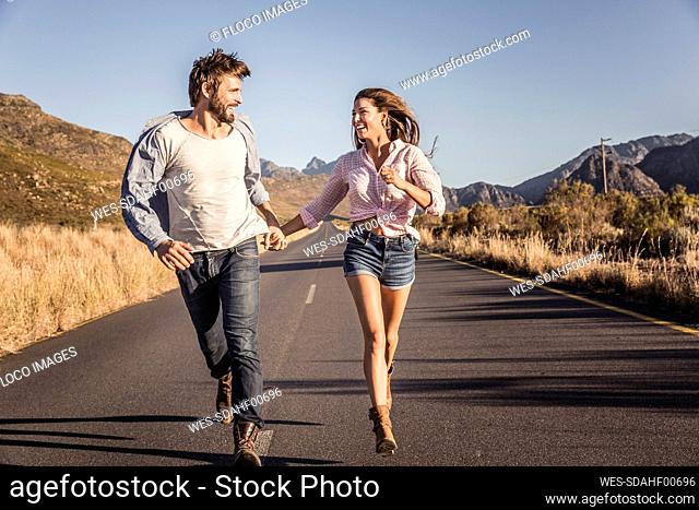 Happy couple running on a country road