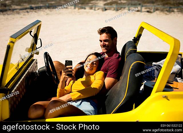 Happy caucasian couple sitting in beach buggy by the sea relaxing
