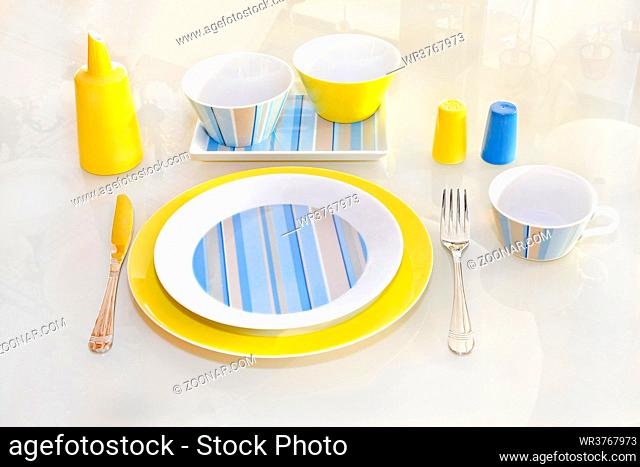 Yellow ceramic plate and tableware at glass table