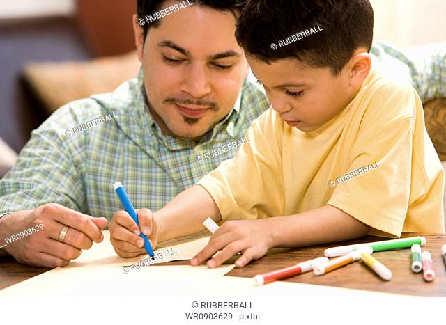 Young boy coloring and drawing with father supervising