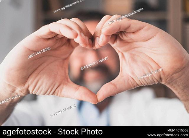 Man doing heart shape gesture with hands. Hand of male doctor making a love symbol. Healthcare worker expressing love and support to patients