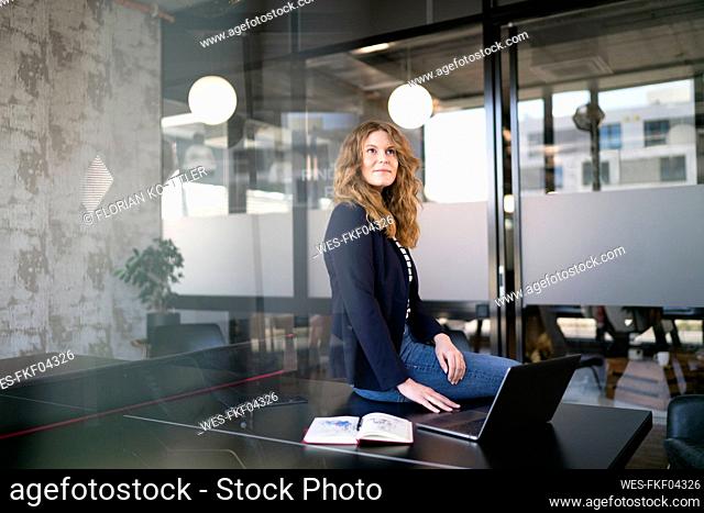 Businesswoman day dreaming while sitting on table at office