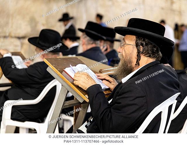 Orthodox Jews pray before the Western Wall in Jerusalem and study the Torah. The Western Wall is considered the holiest place of Judaism