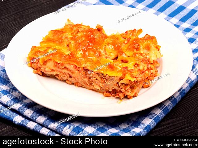 Close-up of a traditional lasagna made with minced beef bolognese sauce on a white plate