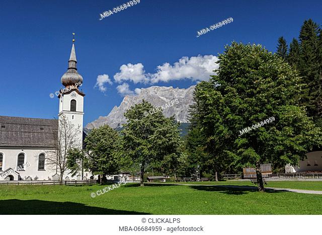 Typical church of alpine village surrounded by peaks and woods Garmisch Partenkirchen Oberbayern region Bavaria Germany Europe