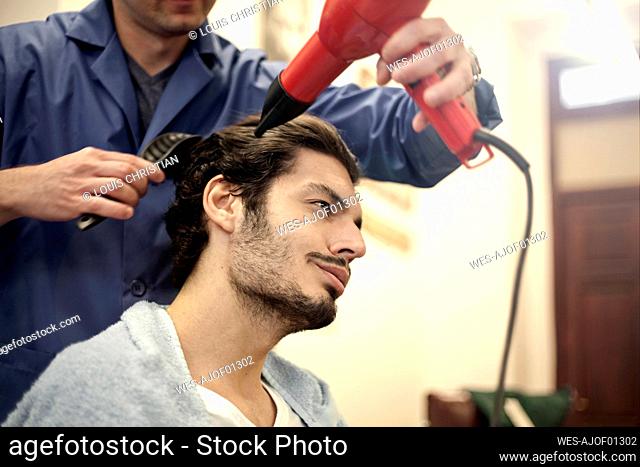 Barber drying hair of male customer